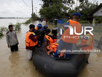 Police officers evacuate an elderly man during floods in Pebayuran sub-district, Bekasi regency, West Java, on February 22, 2021. Massive fl...