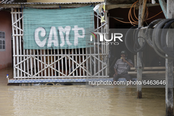 A man enjoy his food in front of his house during floods in Pebayuran sub-district, Bekasi regency, West Java, on February 22, 2021. Massive...