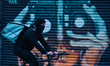 A man wearing a face mask cycles by a closed shop in Dublin city center during Level 5 Cov...