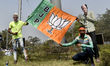 BJP activists pose in front of a camera with a BJP flag during a mass meeting of the Bhara...