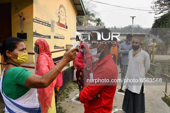 A health worker checks the body temperature of a voter, as a preventive measure against the COVID-19 coronavirus, before casting her ballot... by Anuwar Hazarika/NurPhoto