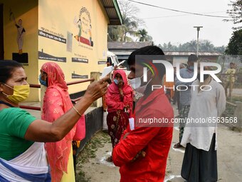 A health worker checks the body temperature of a voter, as a preventive measure against the COVID-19 coronavirus, before casting her ballot... by Anuwar Hazarika/NurPhoto