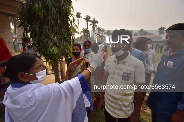 A health worker checks the body temperature of a voter, as a preventive measure against the COVID-19 coronavirus, before casting her ballot... by Anuwar Hazarika/NurPhoto
