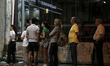 People wait in line at an ATM at 2.15 am outside a National bank branch in a neighborhood...