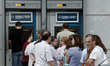 People wait in line at an ATM outside a National bank branch in a neighborhood at Ilioupol...