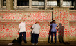 A group of nurses draw red hearts representing individual coronavirus deaths onto the newl...
