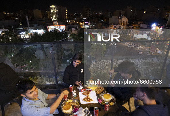Iranian youth living in the holy city of Qom, 145Km (90 miles) south of Tehran, speak with each other as they sit at a fast-food restaurant...