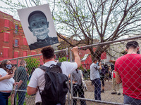 A man holds a sign in the air while he listens to an organizer speak as people gather at Washington Park in memorial and then march to where...
