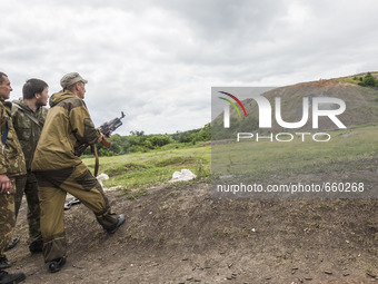 Soldiers shoots a grenade with the assistance of a military instructor of the DPR army in the outskirts of Donetsk city on June 29, 2015. (