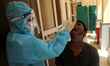 A health worker collects a swab sample of a man for COVID-19 test, amidst the spread of co...