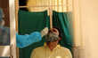 A health worker collects a swab sample of a man for COVID-19 test, amidst the spread of co...