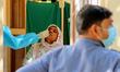 A health worker collects a swab sample of a woman for COVID-19 test, amidst the spread of...