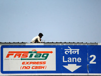 A worker gives the final touches to the roof of a toll plaza with FASTag facility, at KMP Expressway in Ghaziabad on the outskirts of New De...