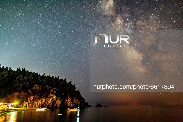 The Milky Way in the dark night sky with the illuminating stars, part of the galaxy that contains our Solar System as seen from a sandy beac...