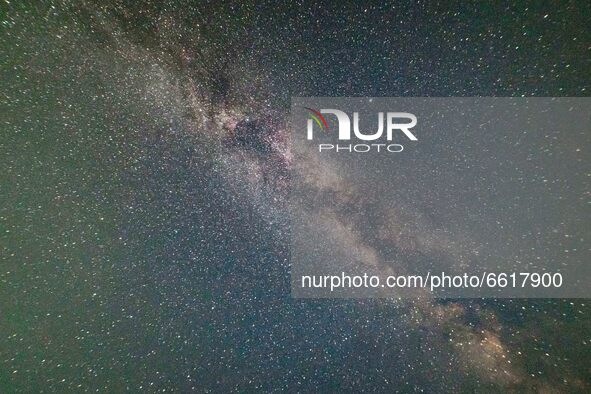 The Milky Way in the dark night sky with the illuminating stars, part of the galaxy that contains our Solar System as seen from a sandy beac...