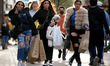 A woman gestures while carrying bags of shopping along a busy Oxford Street in London, Eng...