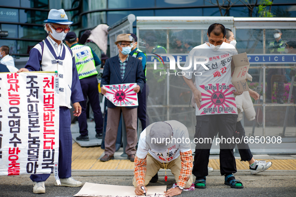 Protesters hold Rising Sun flags that say the Japanese Government Should Drink Fukushima Radioactive Contaminated Water during a protest aga...