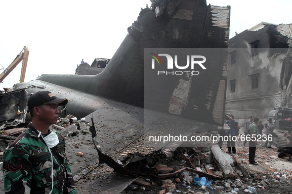Indonesian military personnel standing beside the ruins of Indonesian aircraft C-130 Hercules day after the crash in Medan, North Sumatra, I...