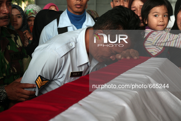Indonesian men weep beside the coffin mourning the body of the bodies of military personnel, one of the victims of the collapse of the C-130...