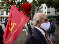 A man wearing a face mask holds flag and red carnations during a demonstration to commemorate the anniversary of Portugal's Red Carnations r...
