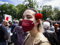 A woman wearing a face mask holds a red carnation in her hair during a demonstration to commemorate the anniversary of Portugal's Red Carnat...