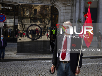 A man wearing a face mask holds flag and red carnations during a demonstration to commemorate the anniversary of Portugal's Red Carnations r...