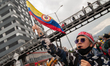 a demonstrator waves a colombian flag with a head wraist that reads "National Strike no mo...