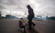 A woman wearing a Colombian flag cries due to tear gas in the middle of a riot police ESMA...
