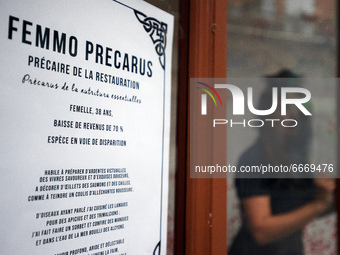 An actress plays in the store front of a restaurant. The placard reads 'Femmo precarus: restaurant's precarious worker'.  Disguised culture...