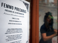 An actress plays in the store front of a restaurant. The placard reads 'Femmo precarus: restaurant's precarious worker'.  Disguised culture...