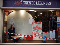 An actress plays in the store front of a comics' bookshop. The placard reads 'withdrawal of the unemployment benefits reform'. Disguised cul...