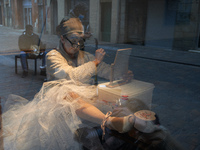 An actress prepares herself inside the storefront of a restaurant. Disguised culture workers (actors, live artists, dancers, musicians, tech...