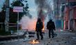 Riot police officers stand behind fire as clashes and riots between riot police, ESMAD, an...