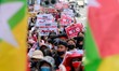 Over one thousand Burmese hold portraits of Aung San Suu Kyi, flash a three fingered salut...