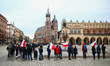 People hold flags celebrating Polish National Flag Day while standing in a long line to re...