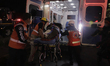 Paramedics transfer an injured person on a stretcher to be taken to a hospital after the c...