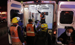 Paramedics transfer an injured person on a stretcher to be taken to a hospital after the c...