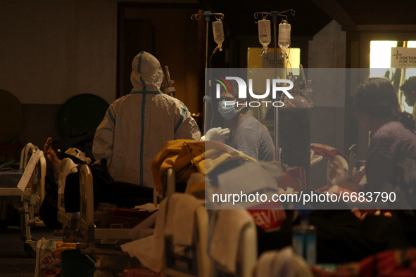A health worker covered in PPE kit takes care of patients inside a banquet hall, temporarily converted into a makeshift quarantine facility...