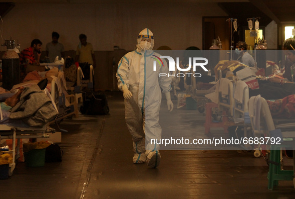 A health worker covered in PPE kit takes care of patients inside a banquet hall, temporarily converted into a makeshift quarantine facility...