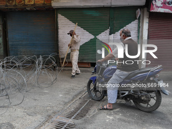 An Indian policeman stop civilian traffic outside Kashmir's grand mosque during Covid-19 lockdown on the last friday of Ramadan in Srinagar,...
