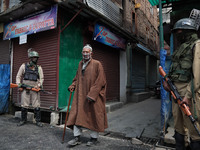 A Kashmiri man walks as Indian troops stand outside Kashmir's grand mosque during Covid-19 lockdown on the last friday of Ramadan in Srinaga...