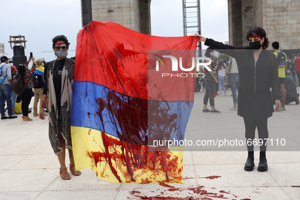 Colombians women hold a Colombian flag while joins a demonstration at Monument of Revolution to protest against the repression and killings...