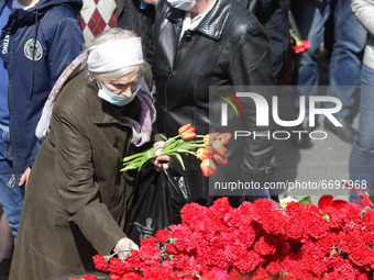 A woman lays flowers to the Monument of Eternal Glory on the Tomb of the Unknown Soldier, during the Victory Day celebration amid the Covid-...