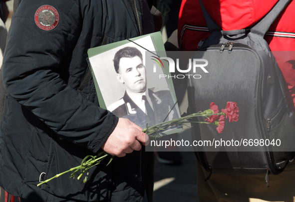 A man holds a veteran's portrait as he carries flowers for laying to the Monument of Eternal Glory on the Tomb of the Unknown Soldier, durin...