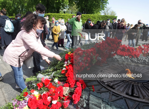 People carry lay flowers to the Monument of Eternal Glory on the Tomb of the Unknown Soldier, during the Victory Day celebration amid the Co...