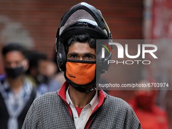 A Man wearing a helmet and Mask walks through a crowded area ahead of Muslim Festival Eid-Ul-Fitr in Sopore, District Baramulla, Jammu and K...