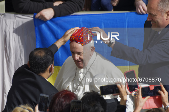 An attendee, left, places a hat on Pope Francis' head in the St. Damaso Courtyard at the Vatican for his weekly general audience, Wednesday,...