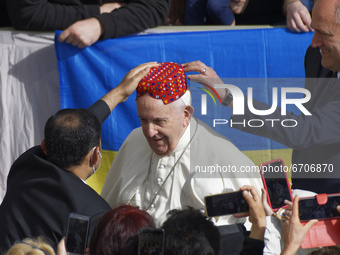 An attendee, left, places a hat on Pope Francis' head in the St. Damaso Courtyard at the Vatican for his weekly general audience, Wednesday,...