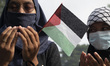 Protesters raise their hands and pray for the safety of Palestinians while participating i...