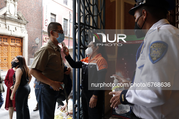 A worker checks temperature of a person before he enter  at Esperanza Iris Theater during the celebration of 103 years that their opening on...